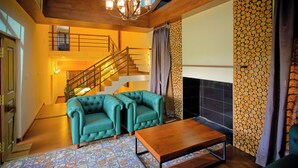 A spacious living area with a wooden staircase, a fireplace, and a patterned floor. - Whispering Pines (Ootacamund)
