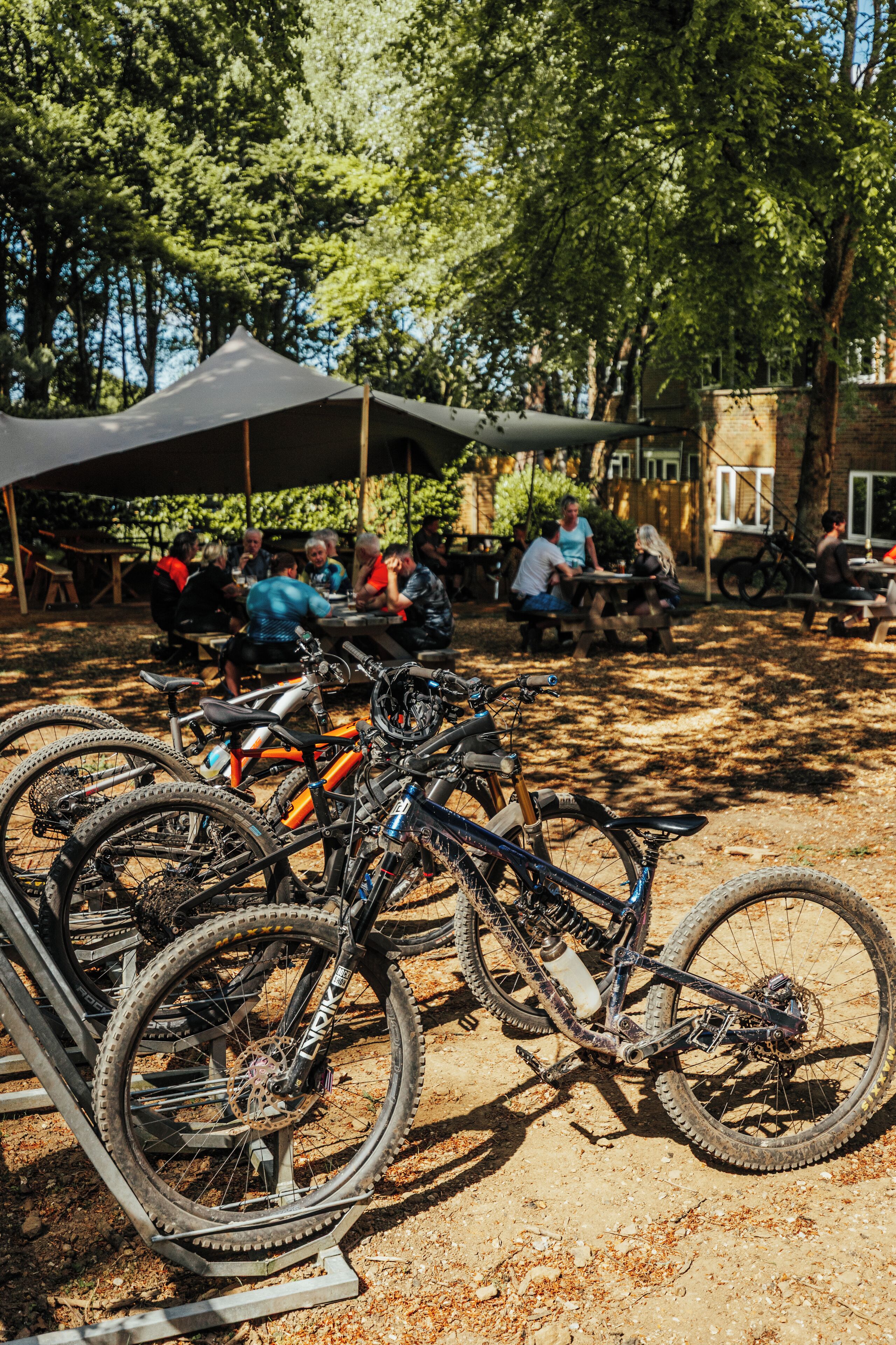 Um grupo de pessoas jantando sob uma tenda, com bicicletas estacionadas perto.