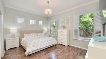 A bedroom with a bed, nightstands, a dresser, a chandelier, and a window with shutters.
