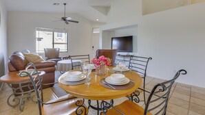 A dining area with a round table set for four, surrounded by metal chairs. A television is mounted on the wall above the table. - Hike, Golf & Relax: Desert Retreat in Cave Creek (Cave Creek)