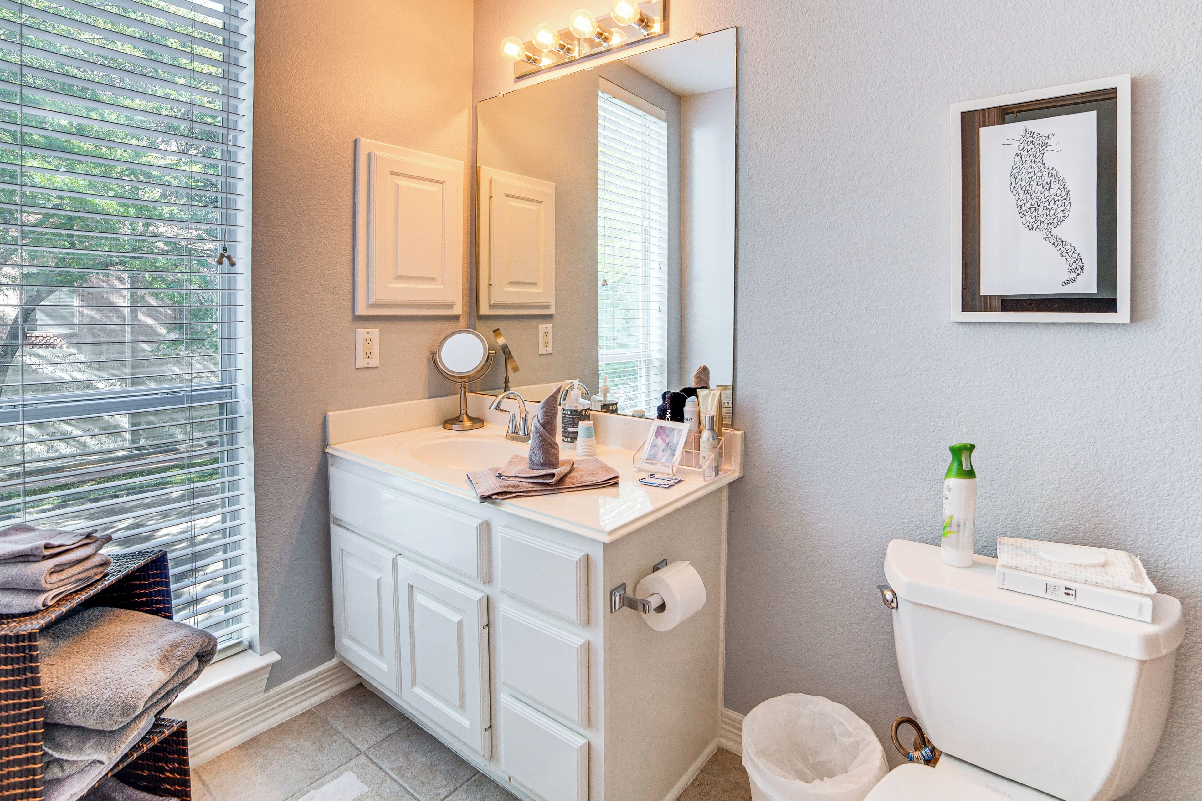 A bathroom with a white vanity, a large mirror, and a framed cat silhouette on the wall.