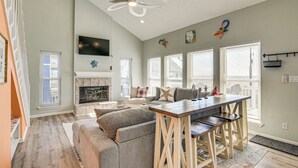 Amplia sala de estar con chimenea, una mesa de comedor con sillas y un ventilador de techo.