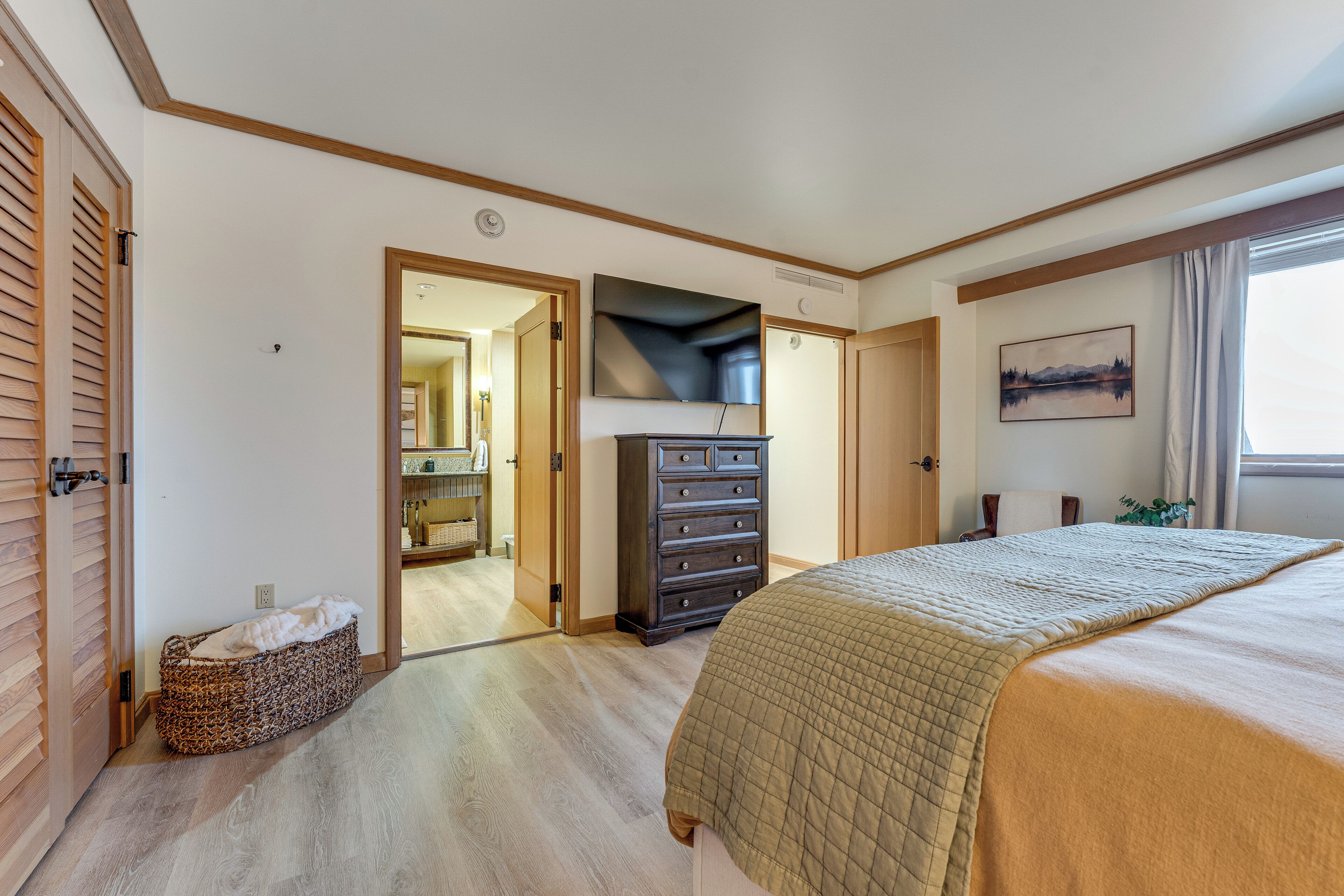 A bedroom with a bed, dresser, and a walk-in closet.