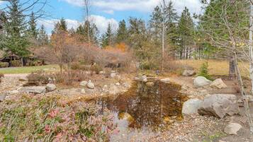 A natural landscape with a pond, rocks, and trees.
