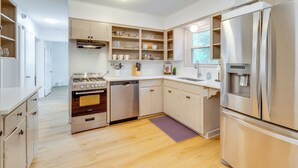 Una cucina moderna con mobili bianchi, elettrodomestici in acciaio inossidabile e pavimento in legno.