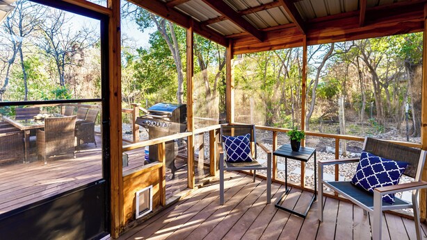 Un terrazzo in legno con mobili da esterno e un barbecue.