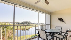 Un balcon avec vue sur un lac, une table avec des chaises et un ventilateur de plafond.