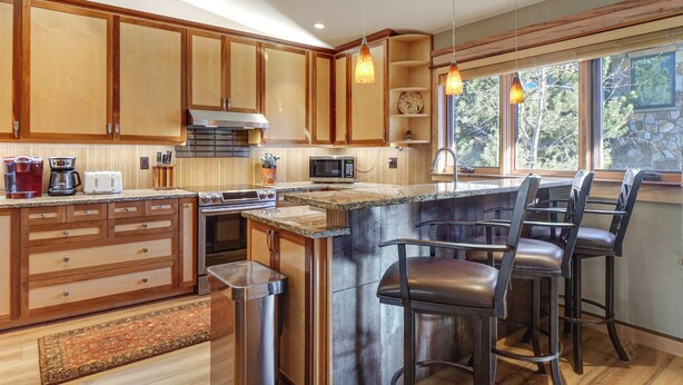 A modern kitchen with wooden cabinets, a central island with bar stools, a microwave, and a coffee maker. - Walk to Main St Frisco: Mount Royal View (Frisco)