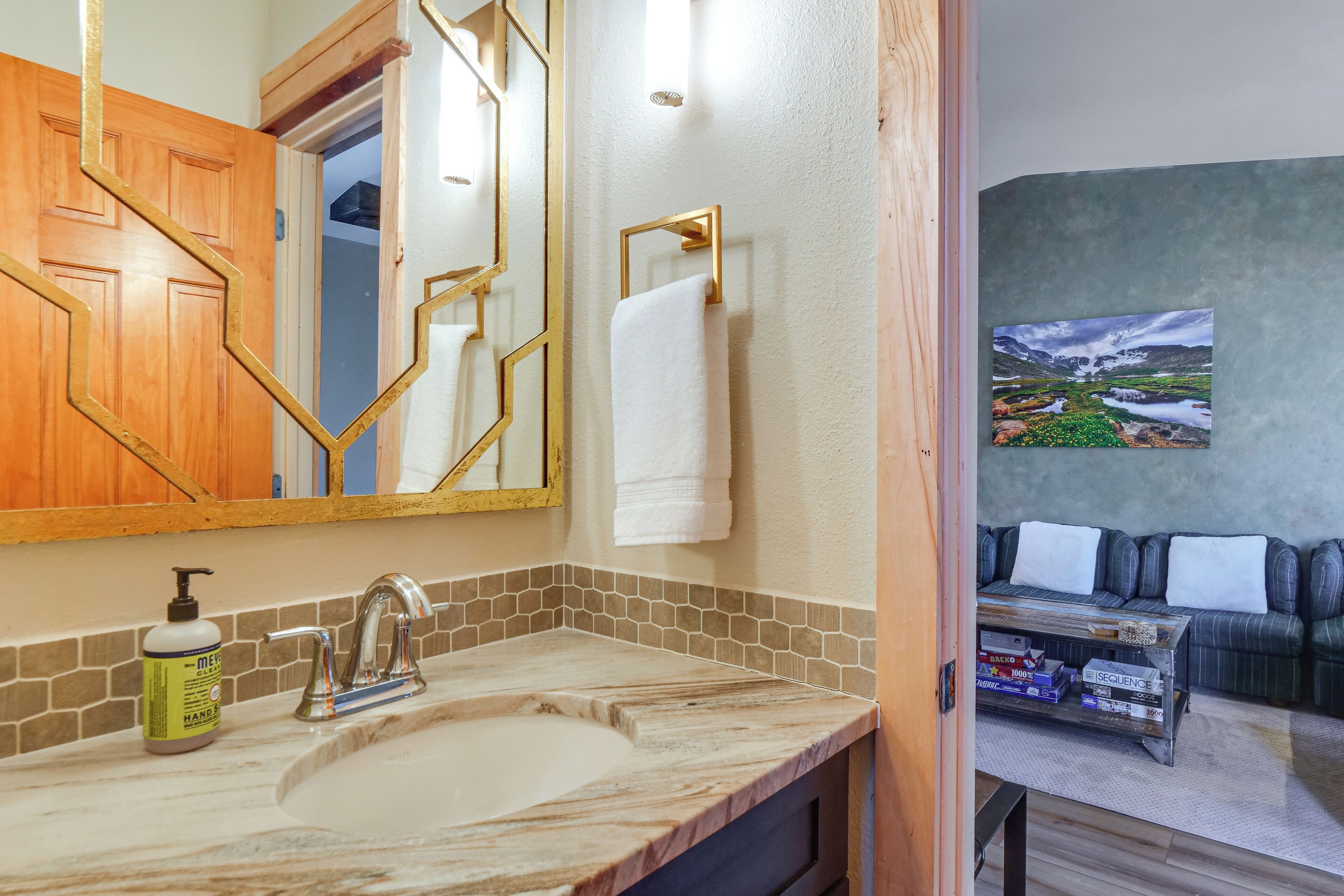 A bathroom with a marble sink, a gold-framed mirror, and a towel hanging on a gold towel rack.