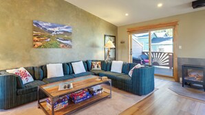 A living room with a sectional sofa, a coffee table, a fireplace, and a large window with a view of a deck and outdoor area. - Walk to Main St Frisco: Mount Royal View (Frisco)