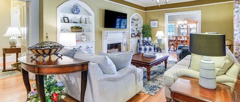 Un salon avec une cheminée, un ventilateur de plafond et un téléviseur.