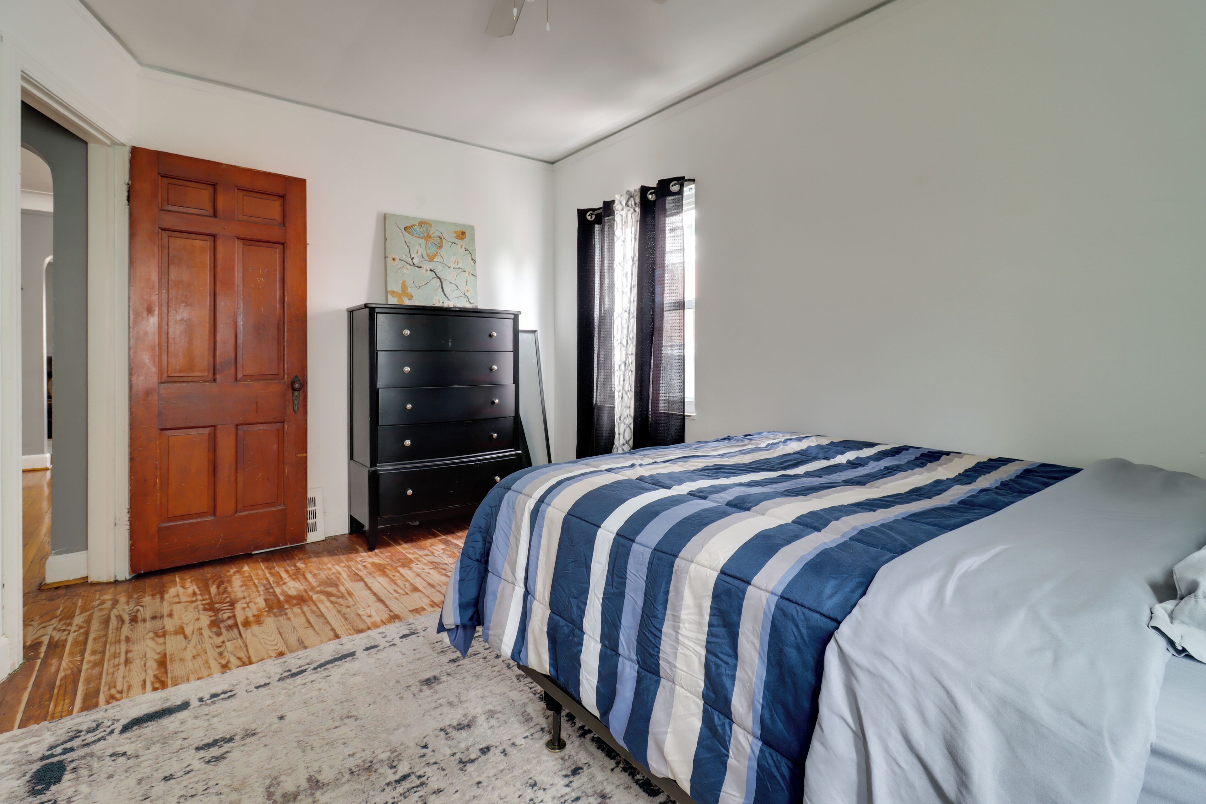 Um quarto com cama, penteadeira e porta.