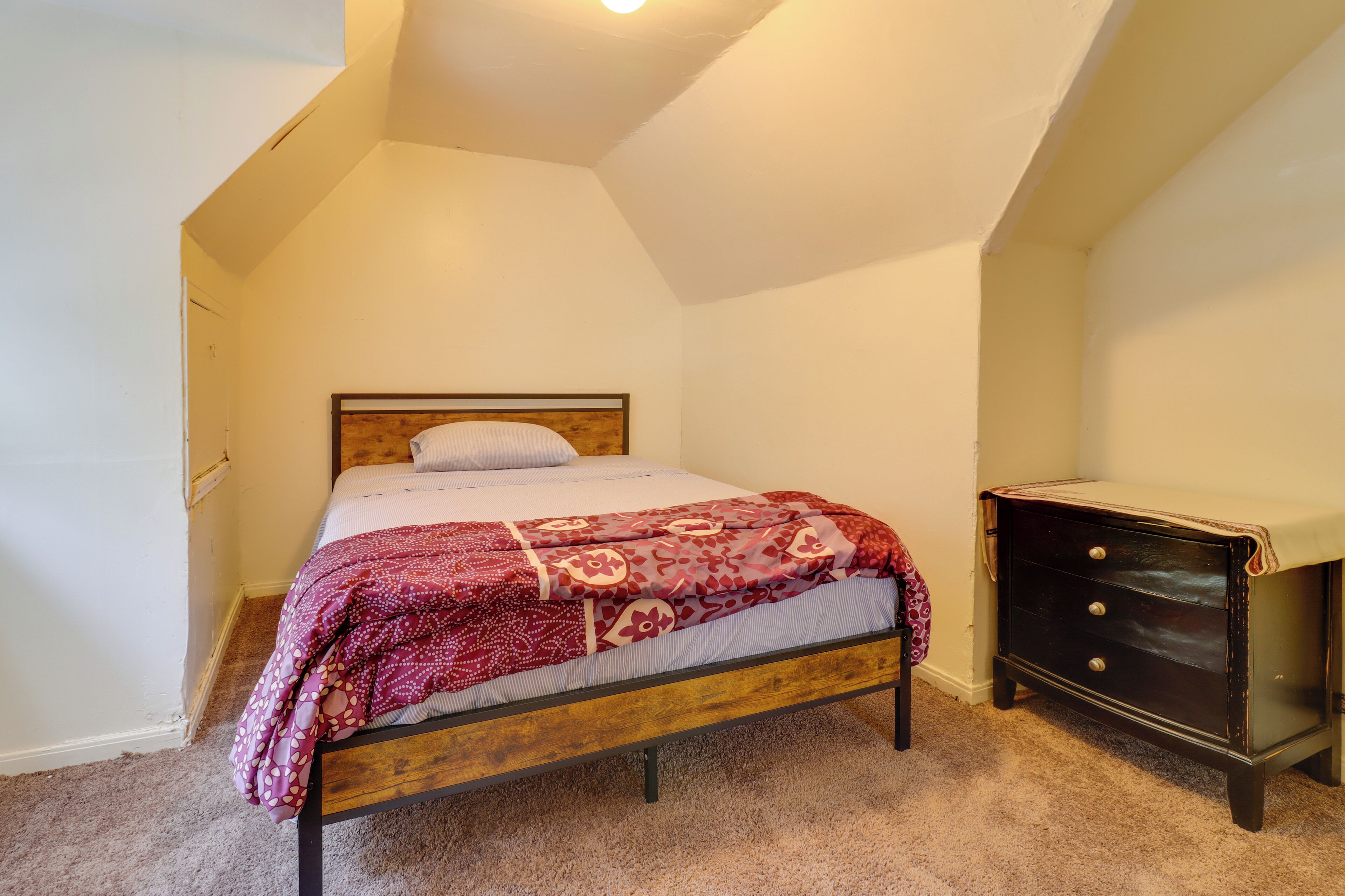 Ein Schlafzimmer mit einem Einzelbett, einem Schminktisch und einer schrägen Decke.