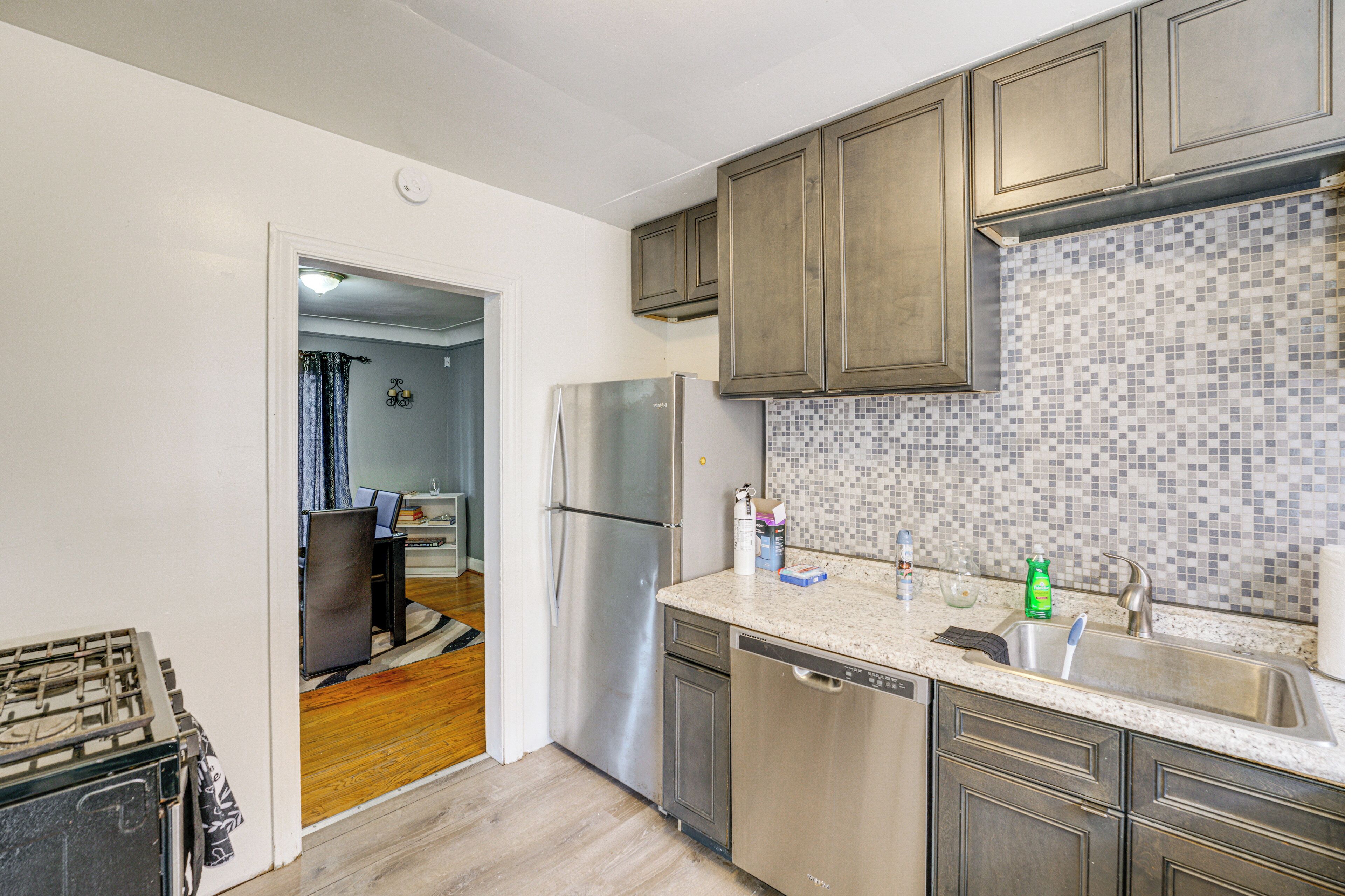 A kitchen with wooden cabinets, a stainless steel refrigerator, and a tiled backsplash.
