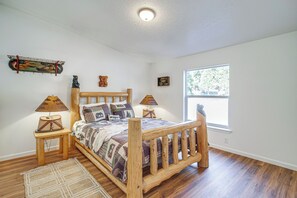 Een slaapkamer met een houten bed, twee nachtkastjes, een raam en een wandplank.