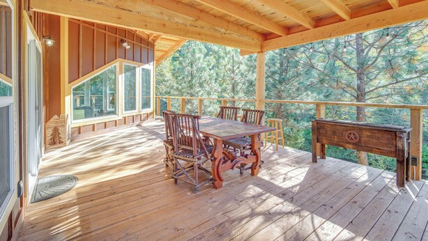 Une terrasse en bois avec une table à manger et des chaises, une petite table et une vue sur les arbres.