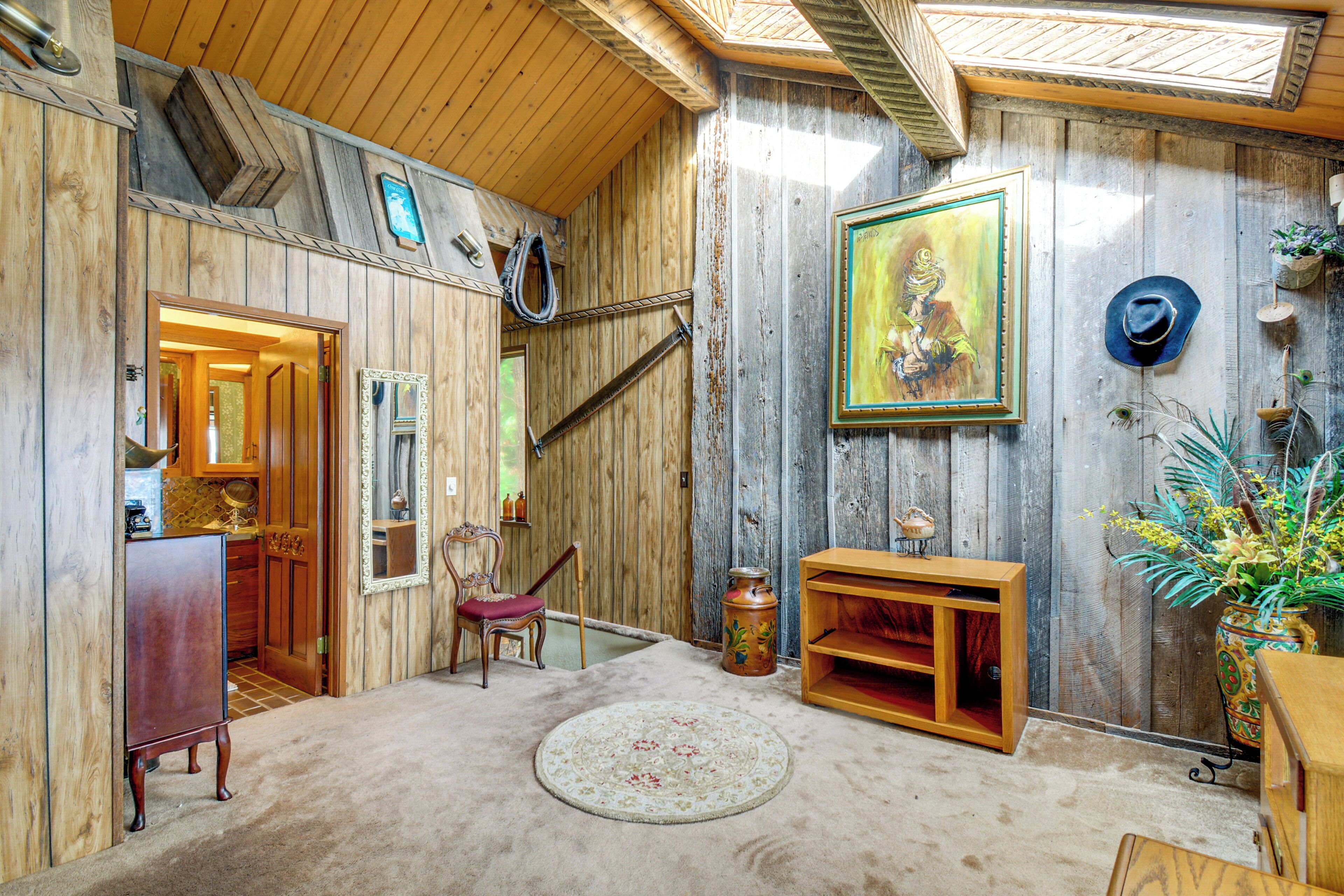 Un intérieur rustique avec des murs en bois, un plafond en bois, un tapis rond, une chaise, un meuble en bois, un tableau et une plante en pot.
