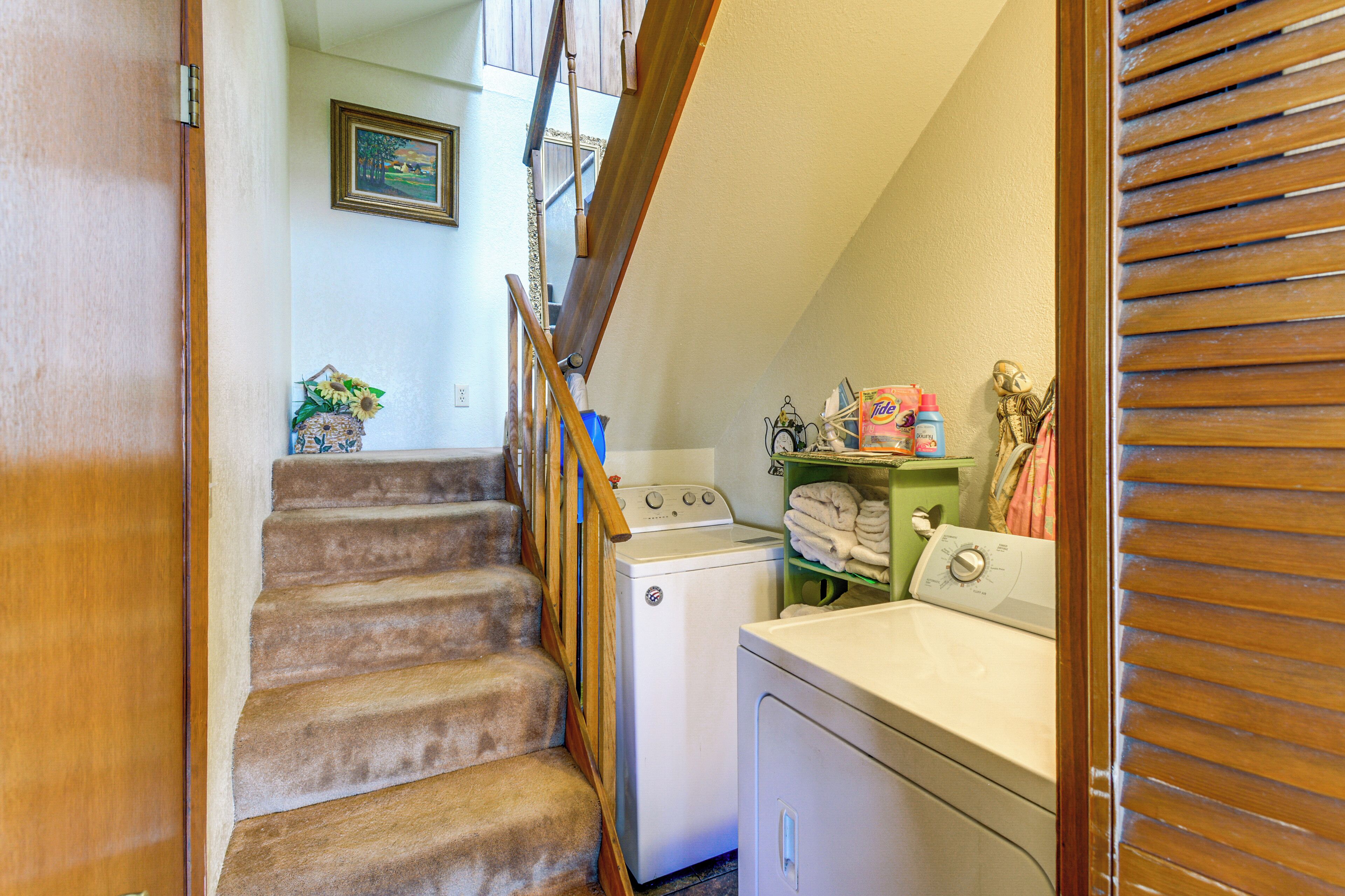 A laundry area with a wooden staircase, a washing machine, and a dryer.
