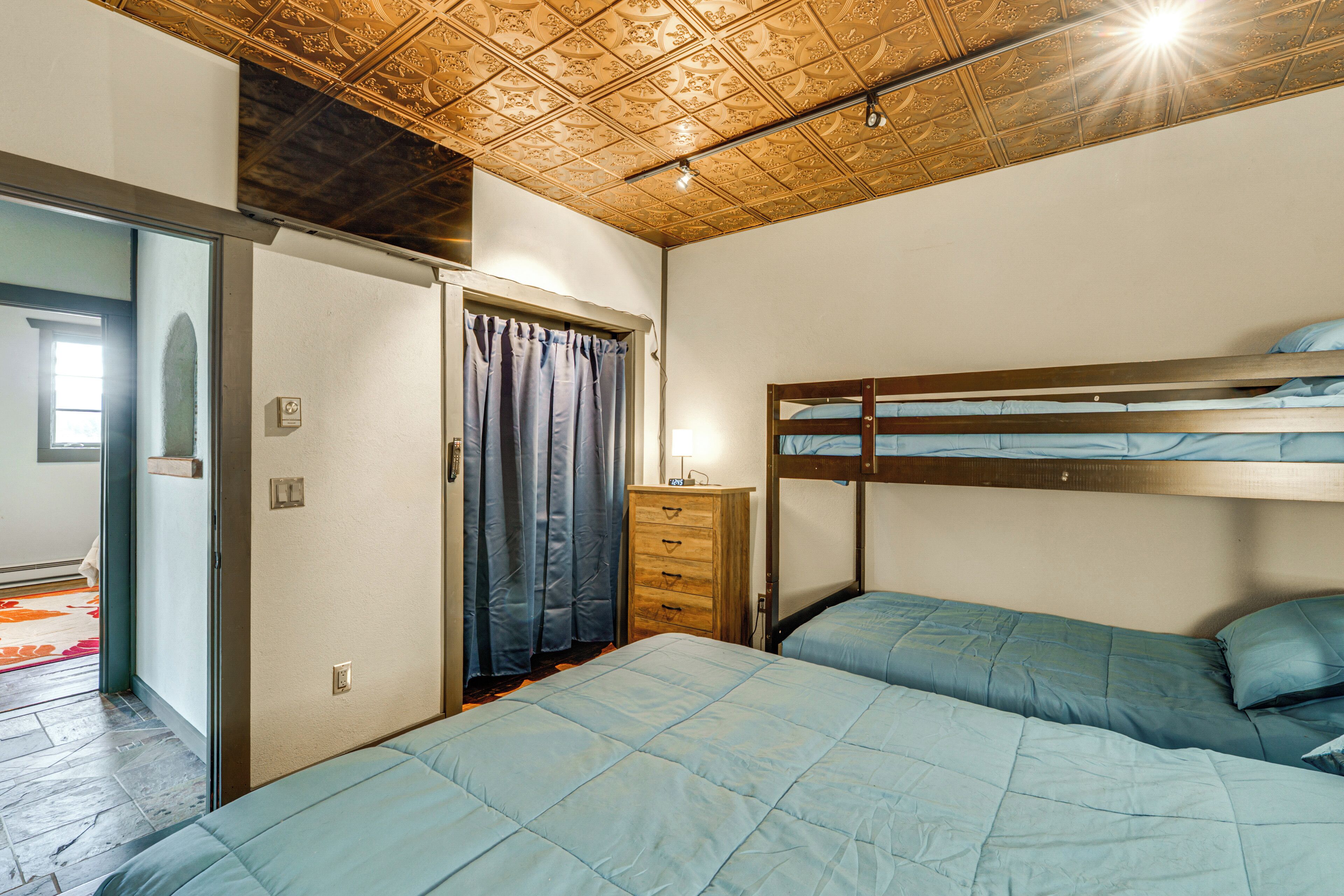 A bedroom with bunk beds, a wooden dresser, and a ceiling with a decorative pattern.