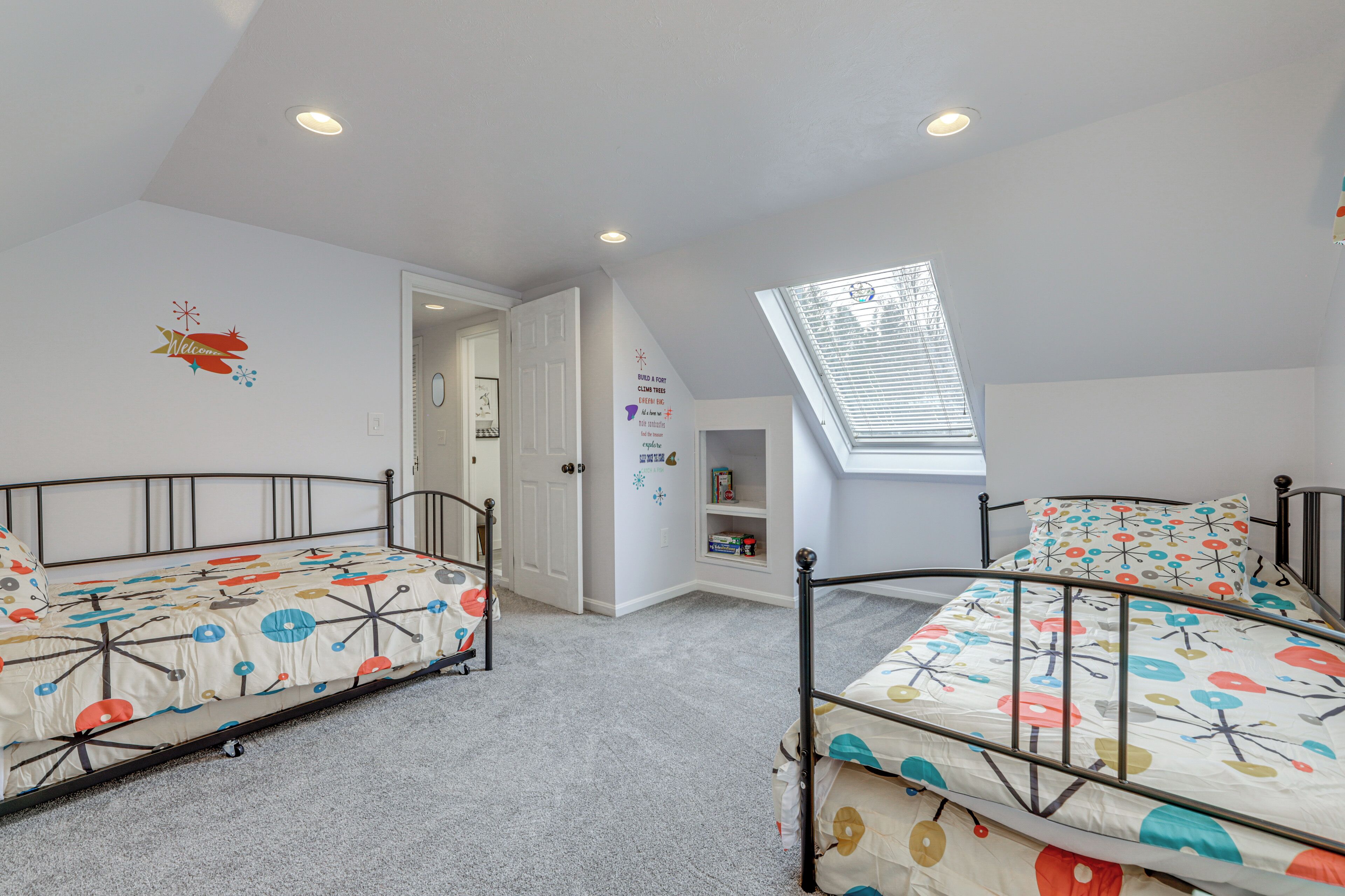 Een slaapkamer met twee bedden, een dakraam en een deur naar een andere kamer.