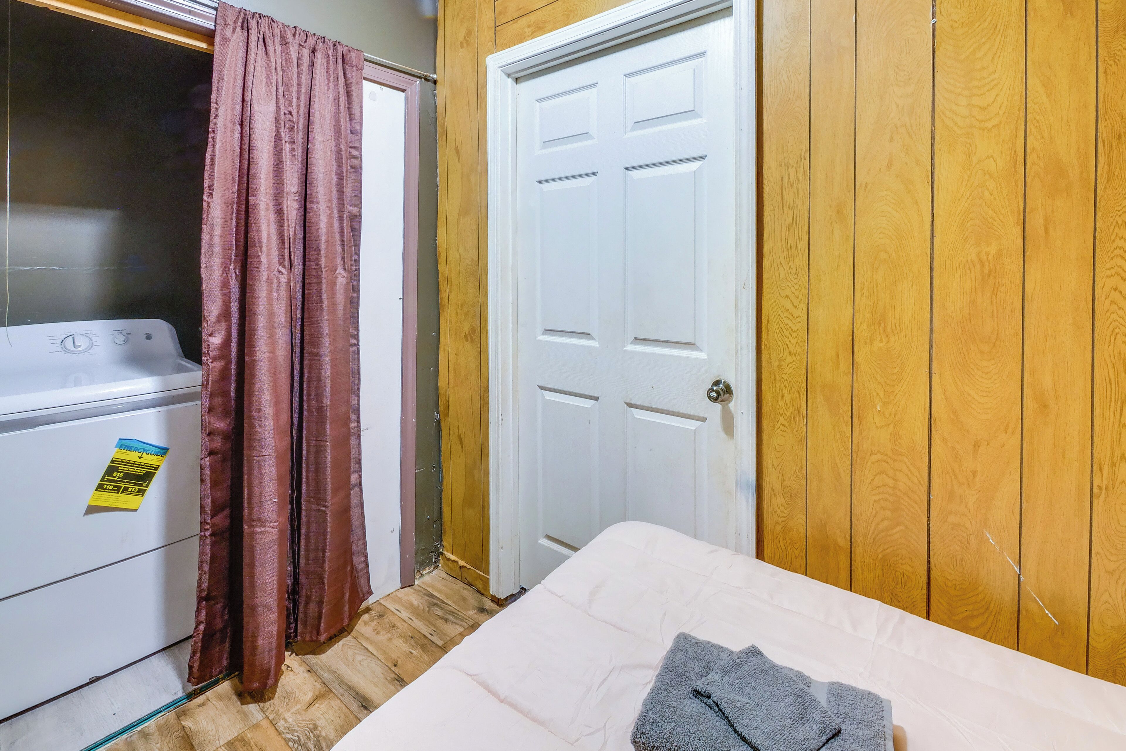 A room with a washing machine, a door, and a bed.