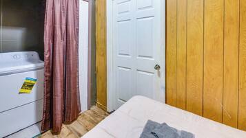 A room with a washing machine, a door, and a bed.