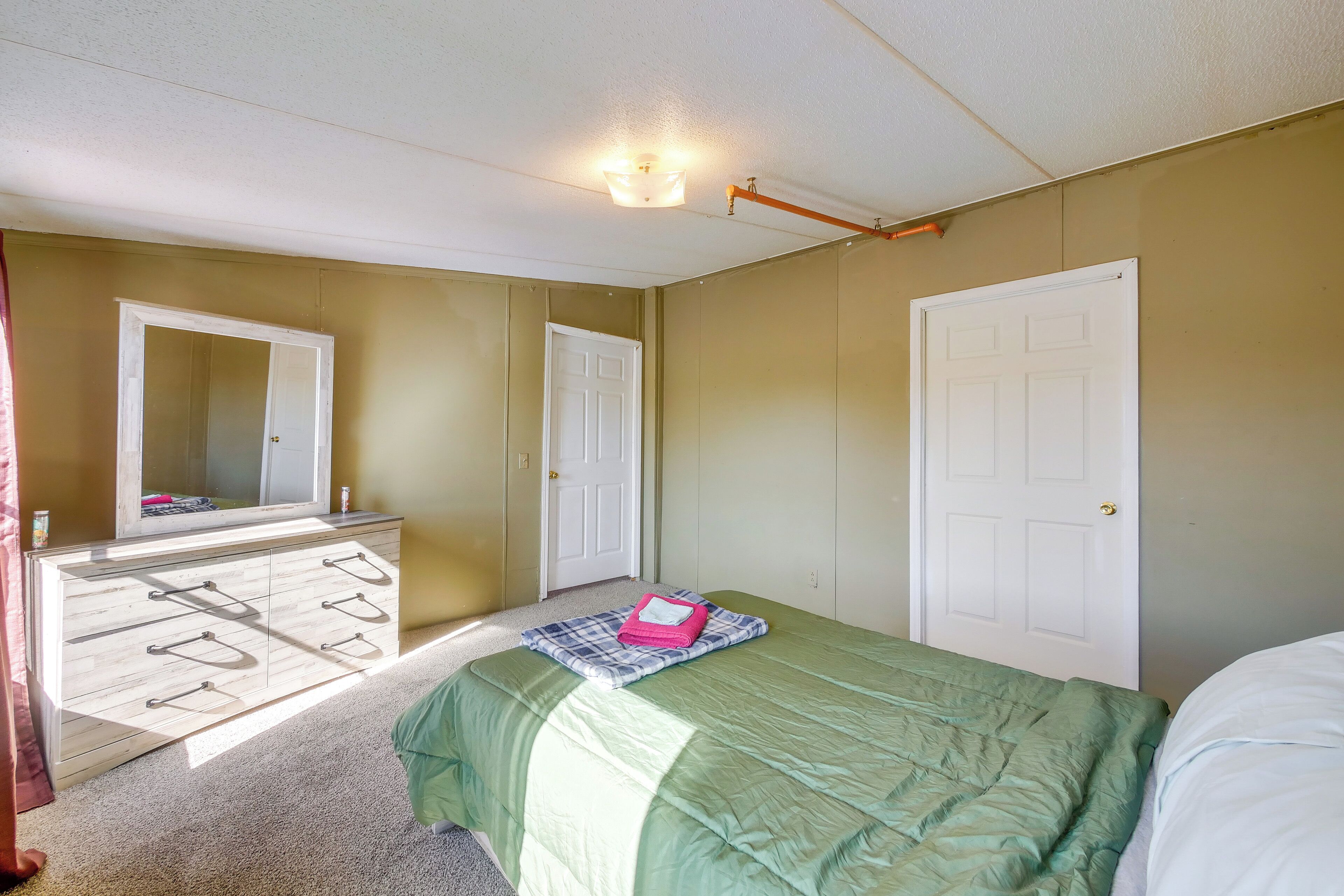 A bedroom with a bed, dresser, and a mirror.