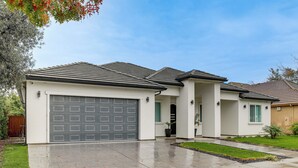 A modern two-story house with a large garage, a well-maintained lawn, and a paved driveway.
