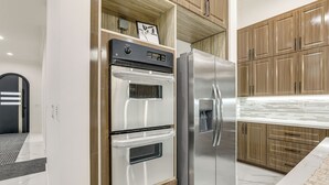 A kitchen with a built-in oven and refrigerator, wooden cabinets, and a marble countertop.