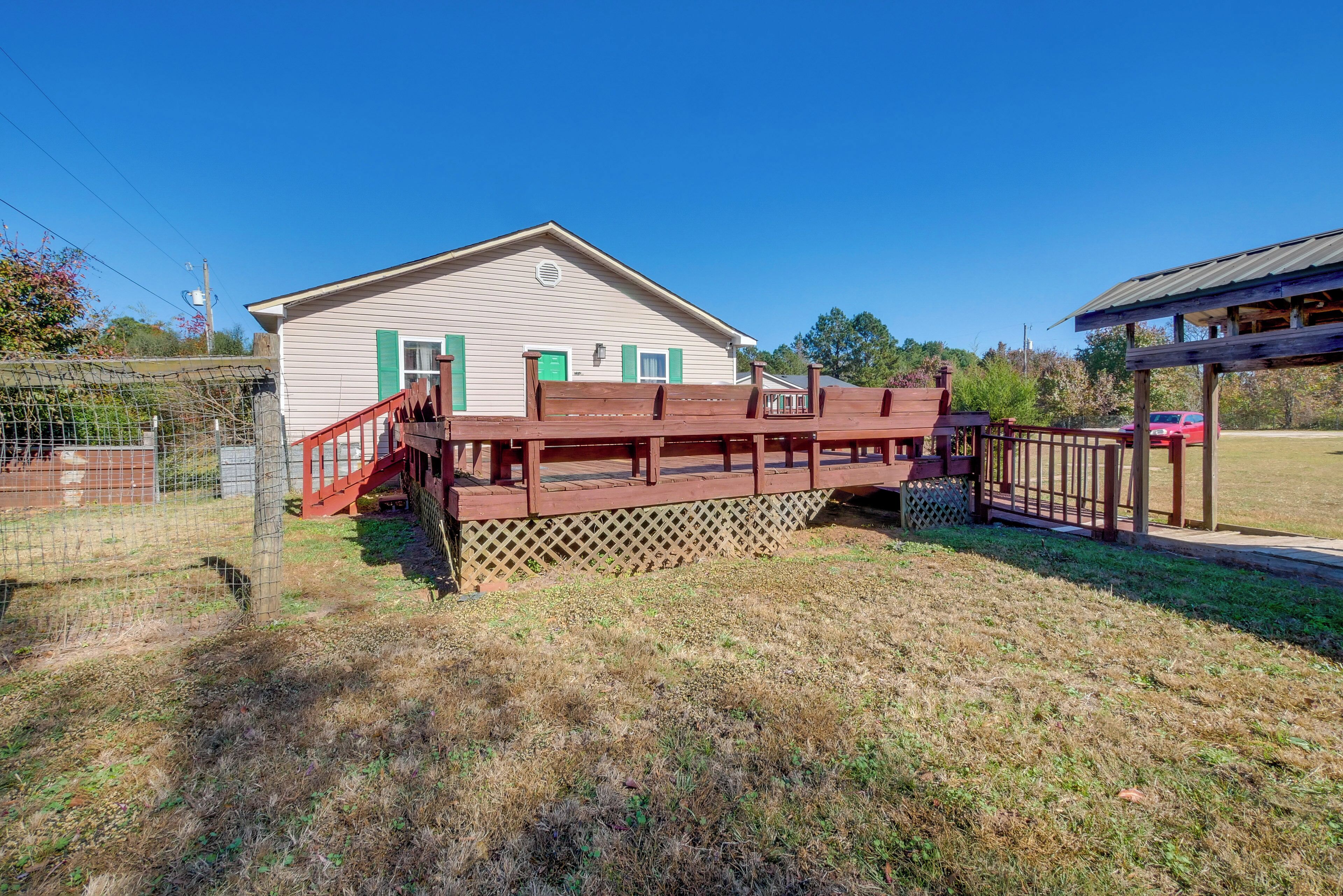 A stable with a wooden deck and a fenced area.