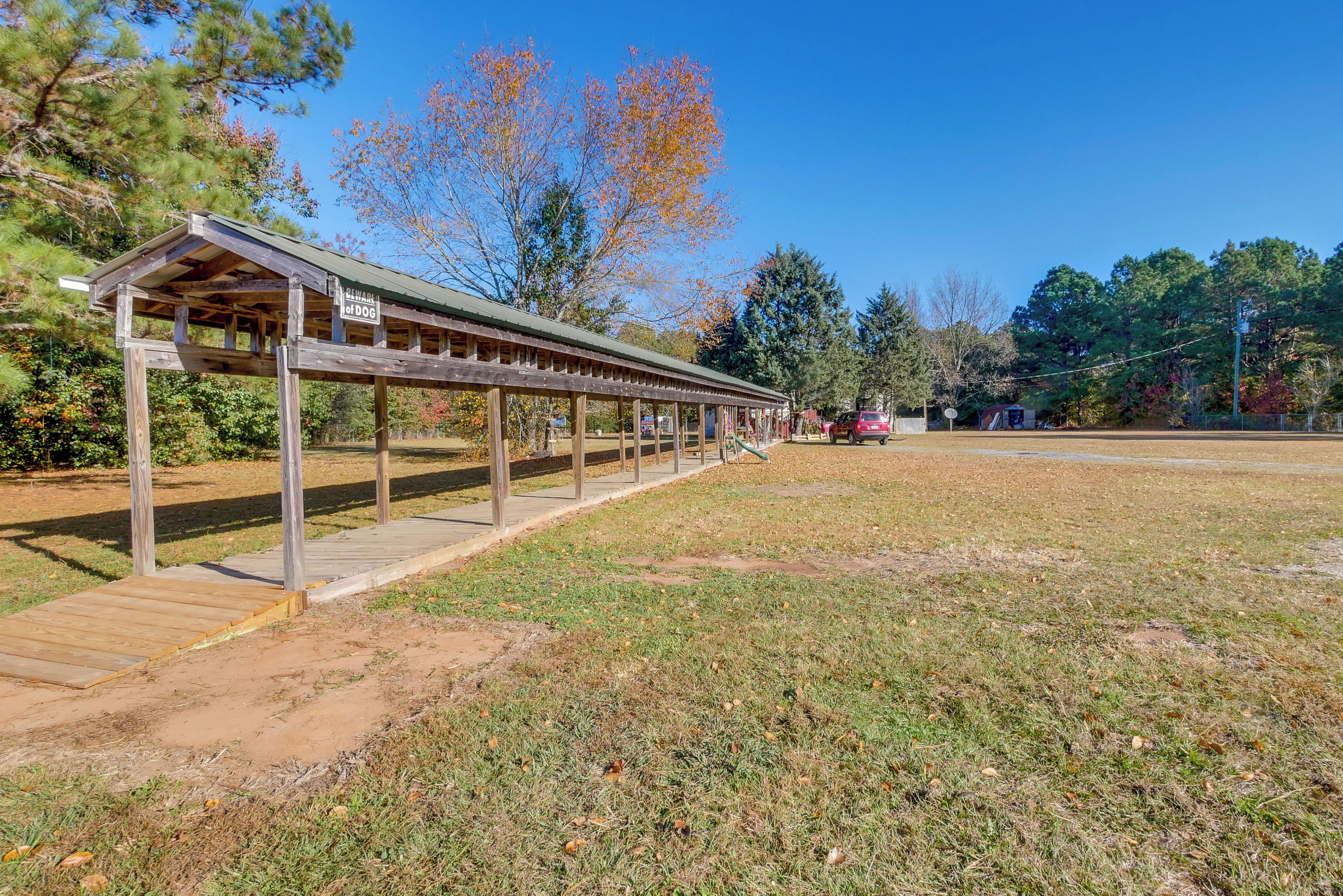 A covered wooden structure with a sign reading "BARN OF DOGS" in a park setting.
