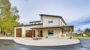 Uma casa moderna com dois andares, varanda coberta, garagem e entrada com calçamento de brita.