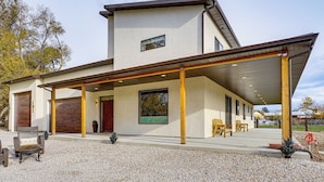 Uma casa moderna de dois andares com varanda coberta, garagem e entrada com jardim em cascalho.