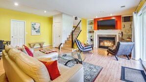 Un salon avec un canapé, des fauteuils, une cheminée et un escalier.