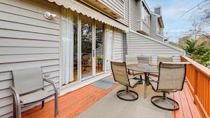 Une terrasse avec une table et des chaises, un espace patio couvert et une porte-fenêtre coulissante.