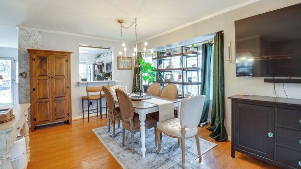 A dining area with a wooden cabinet, a chandelier, and a large window with curtains. - Tranquil Townhouse Retreat w/ Deck in Germantown! (Germantown)