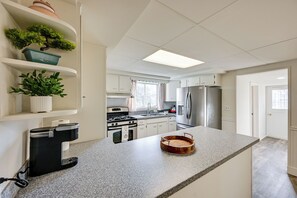 A modern kitchen with white cabinets, a stainless steel refrigerator, a coffee maker, and a potted plant on the shelves. - 3 Mi to Auburn Station! Commuter-friendly Home (Auburn)