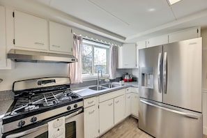 A kitchen with white cabinets, a stainless steel refrigerator, a gas stove, and a window with curtains. - 3 Mi to Auburn Station! Commuter-friendly Home (Auburn)