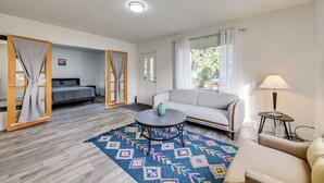A modern living room with a sofa, a coffee table, and a bed with curtains. - 3 Mi to Auburn Station! Commuter-friendly Home (Auburn)