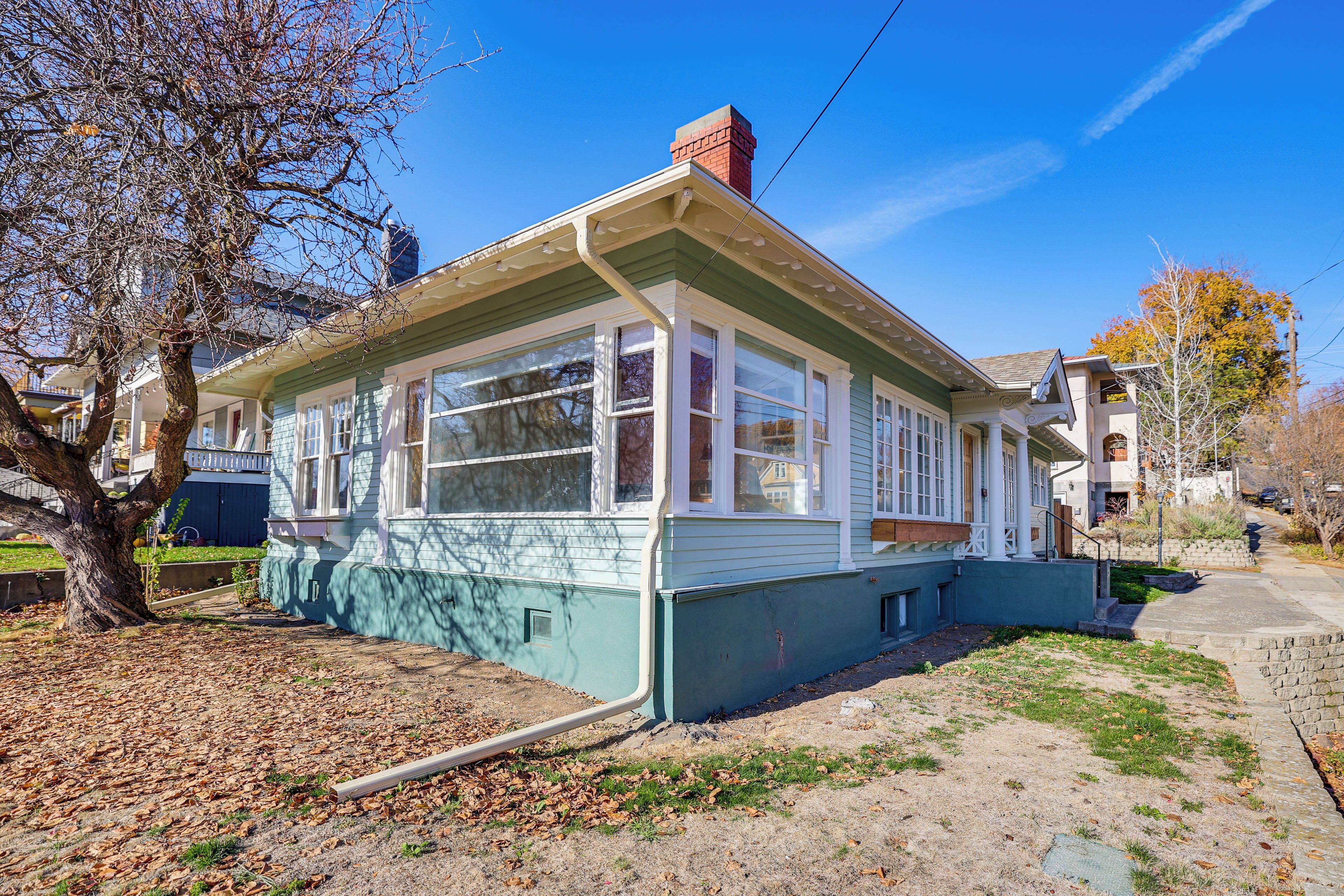 A single-story house with a front porch, a chimney, and a small front yard.