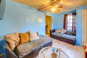 A living room with two sofas, a glass coffee table, and a ceiling fan.