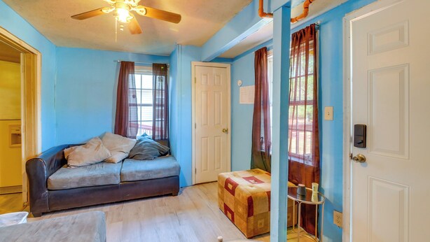 A room with a sofa, ottoman, and a small table with a remote control. - Countryside Escape, 8 Mi to Fvsu & Main Street! (Fort Valley)
