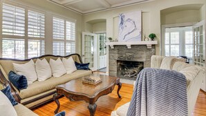 A spacious living room with a fireplace, a sofa, a coffee table, and a large window. - Walk to Coker University & Dtwn! Home w/ Game Room (Hartsville)