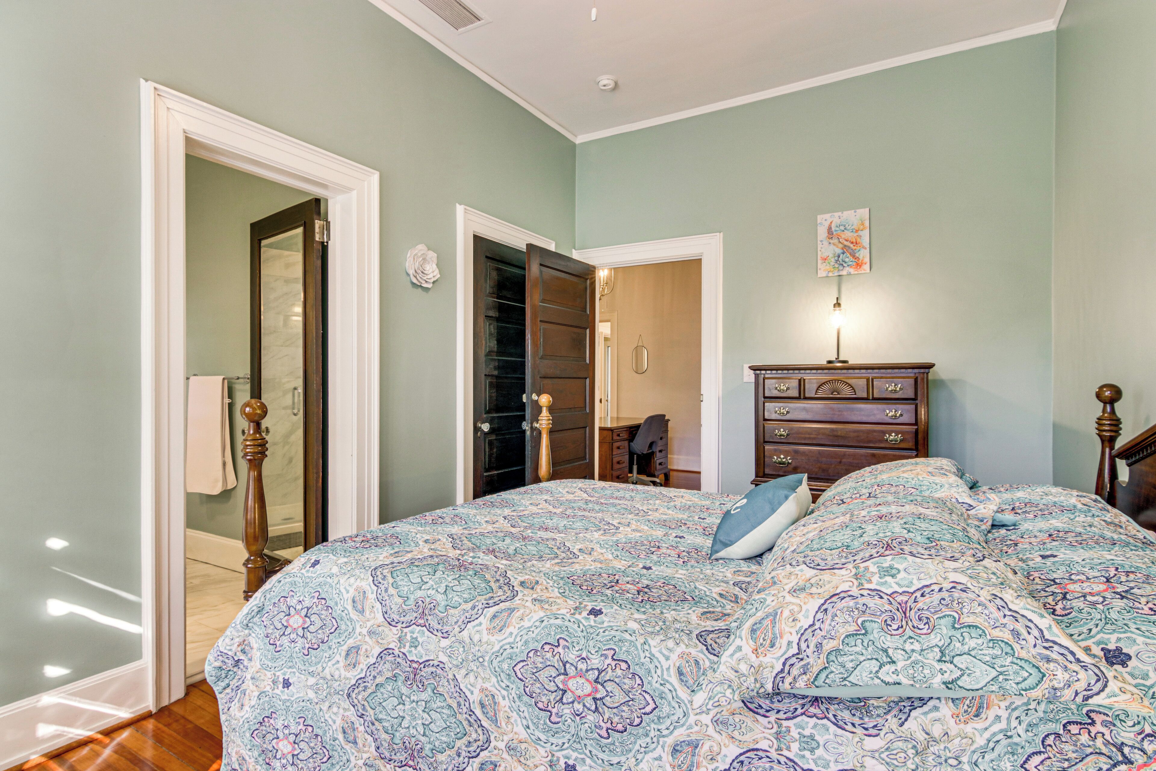 A bedroom with a large bed, a dresser, and a door leading to a closet.