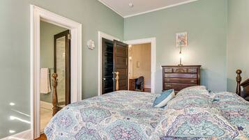 A bedroom with a large bed, a dresser, and a door leading to a closet.