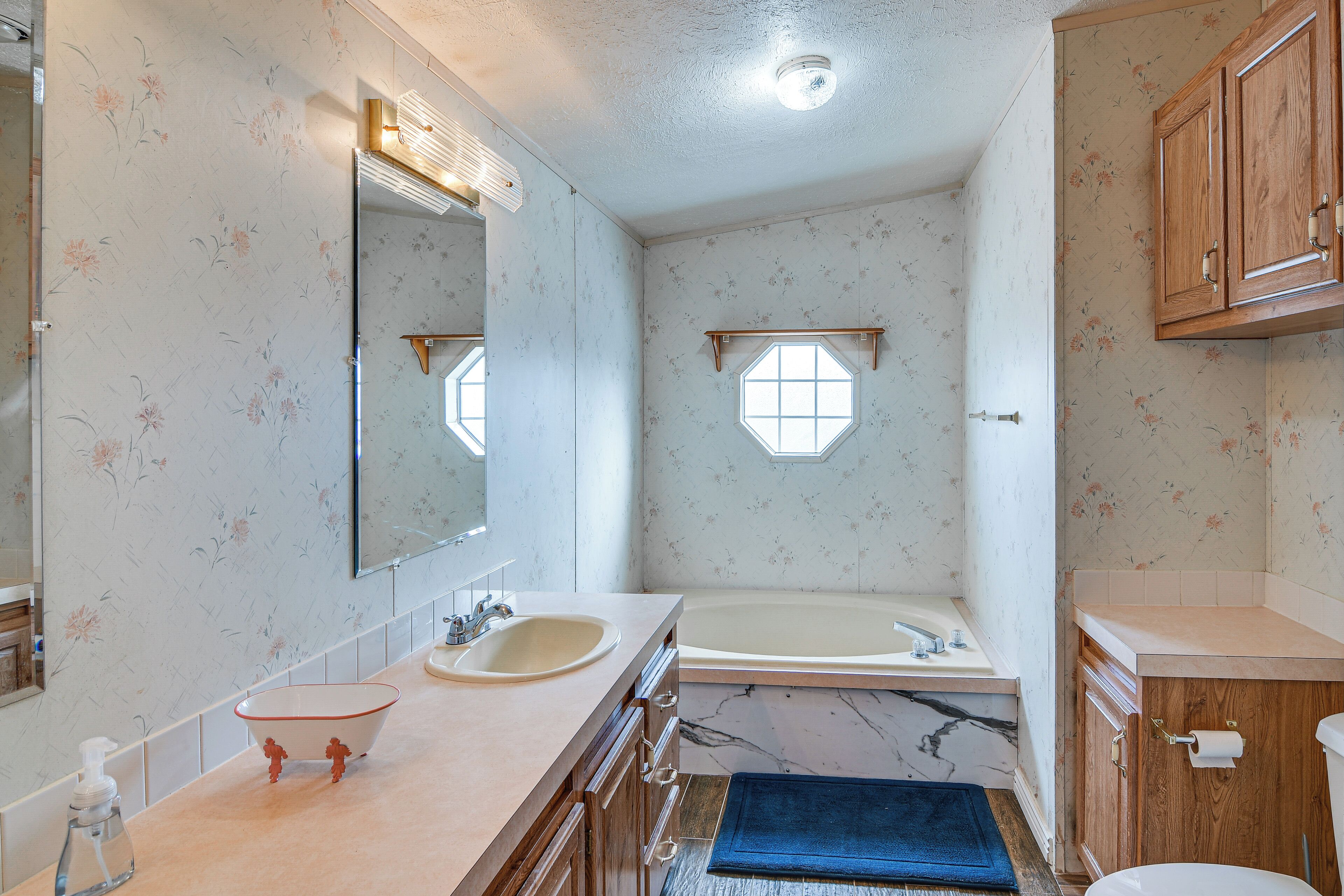 A bathroom with a sink, mirror, and bathtub.