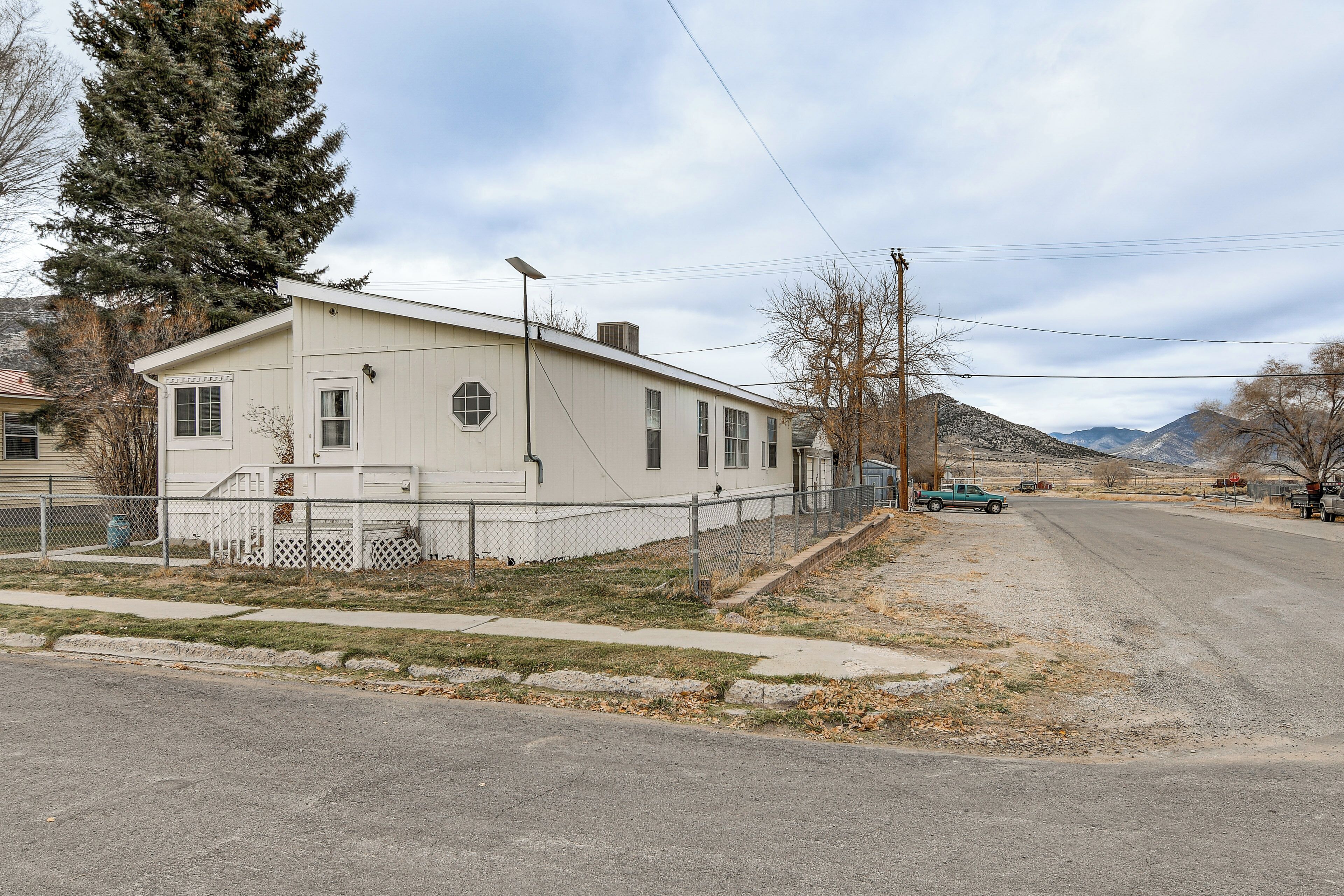 A single-story building with a white exterior, a fenced yard, and a parked truck.