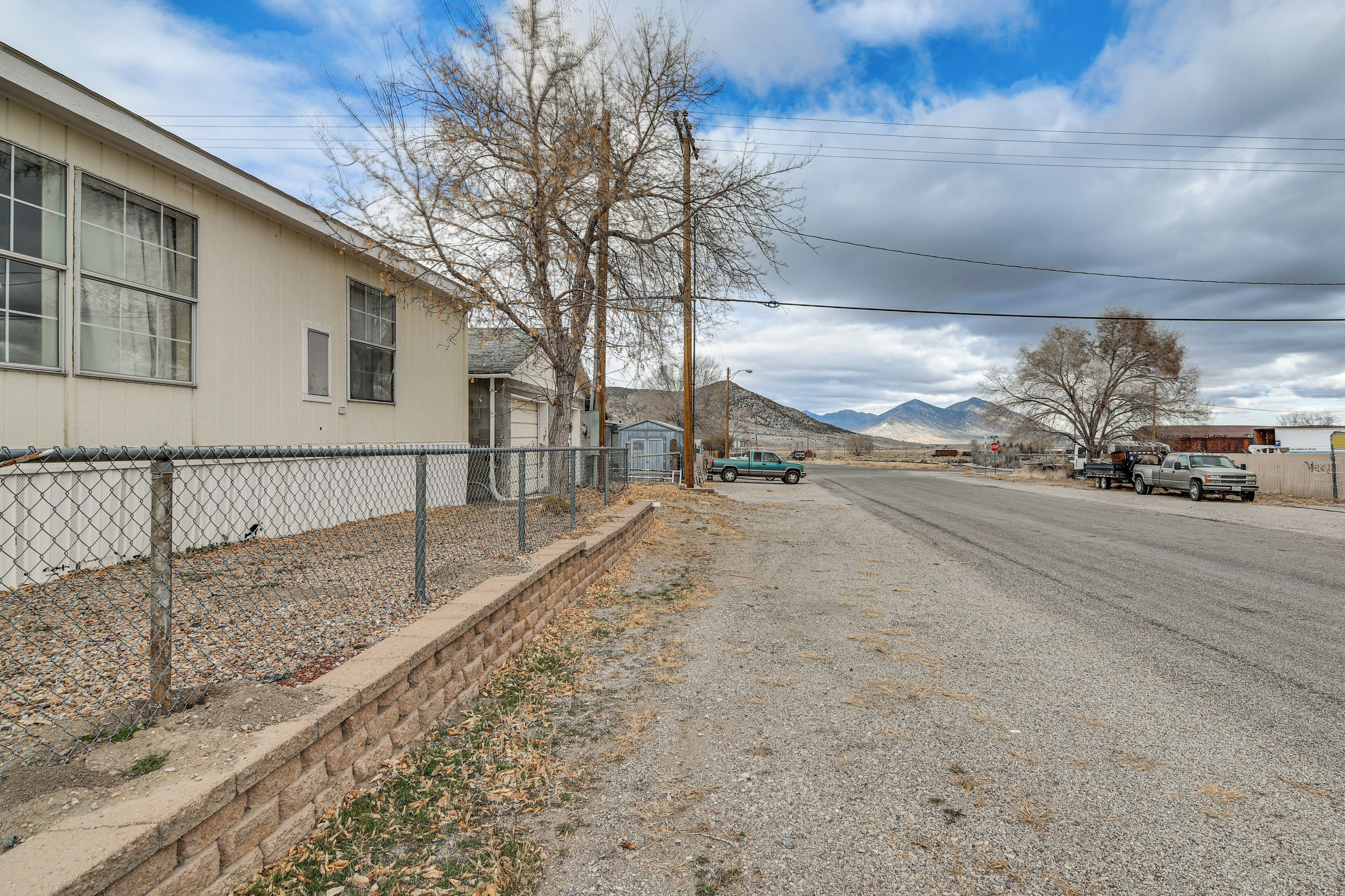 A quiet street with a single-story house, a fence, and a clear sky.