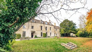 A large stone building with multiple windows and a well-maintained lawn. - Stunning 8-Bedroom Home in Painswick (Painswick)