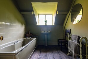 A bathroom with a bathtub, a sink, a mirror, and a window. - Stunning 8-Bedroom Home in Painswick (Painswick)